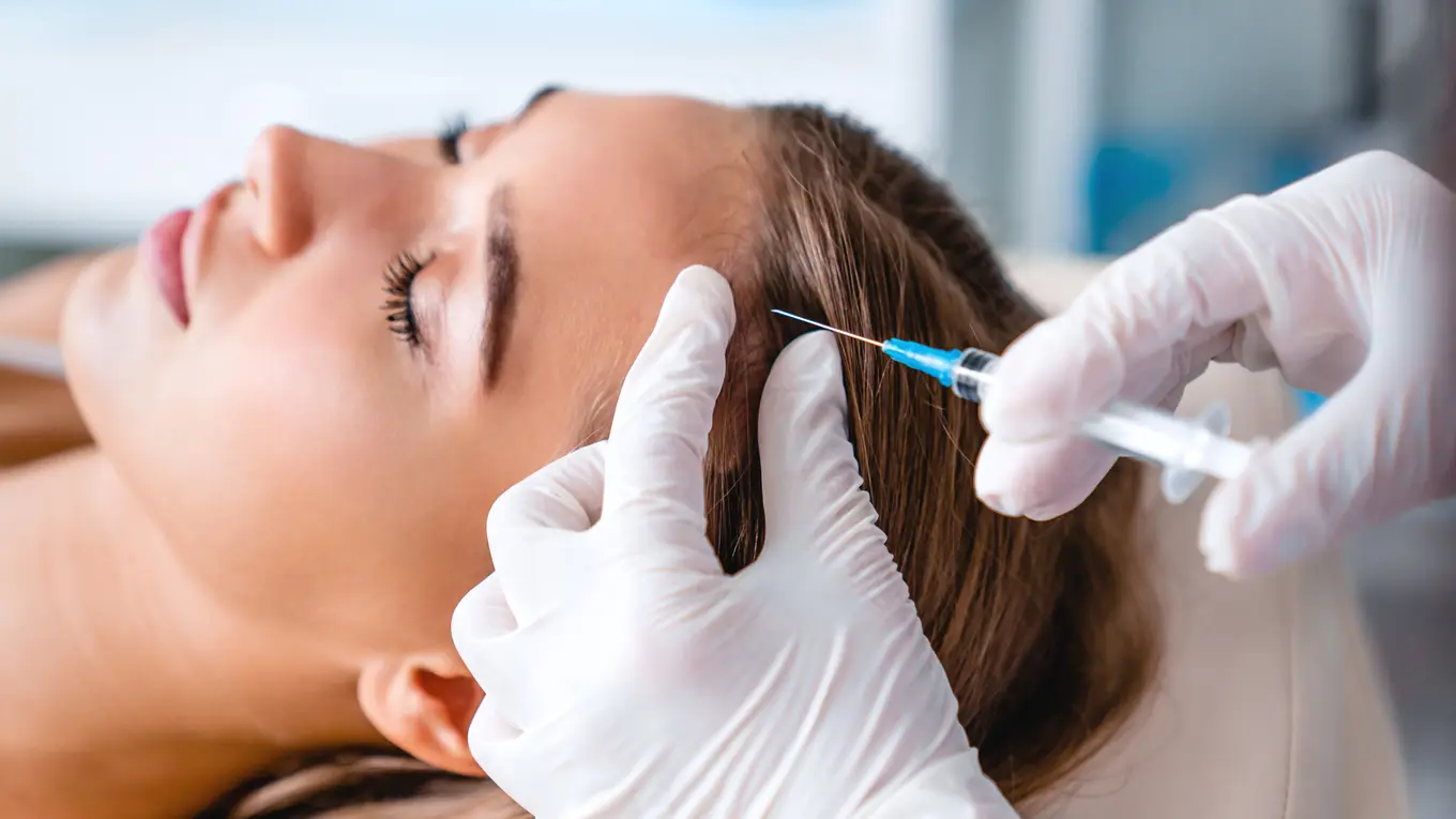 Doctor injecting woman's scalp with syringe
