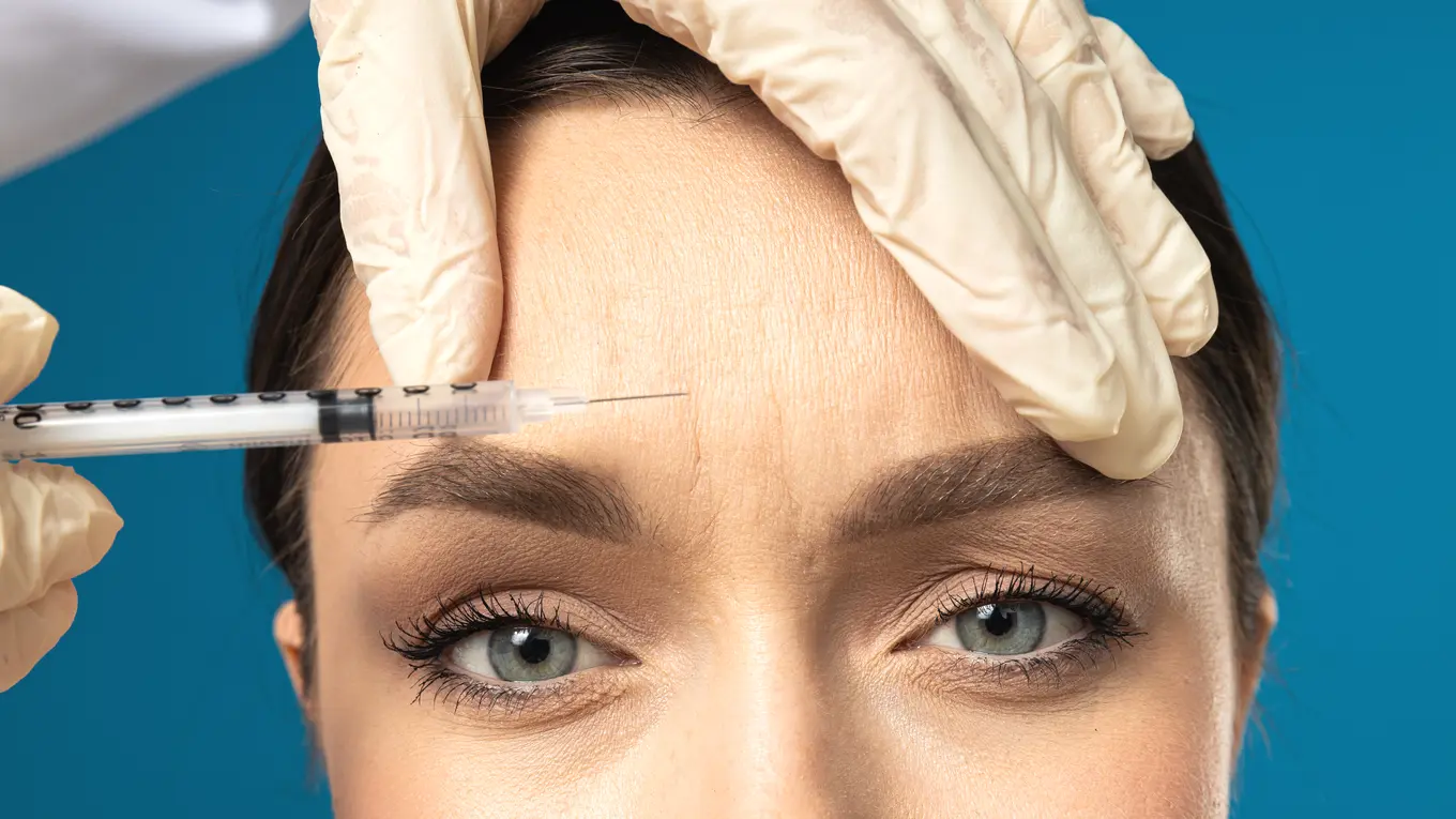 Woman receiving cosmetic injection on forehead