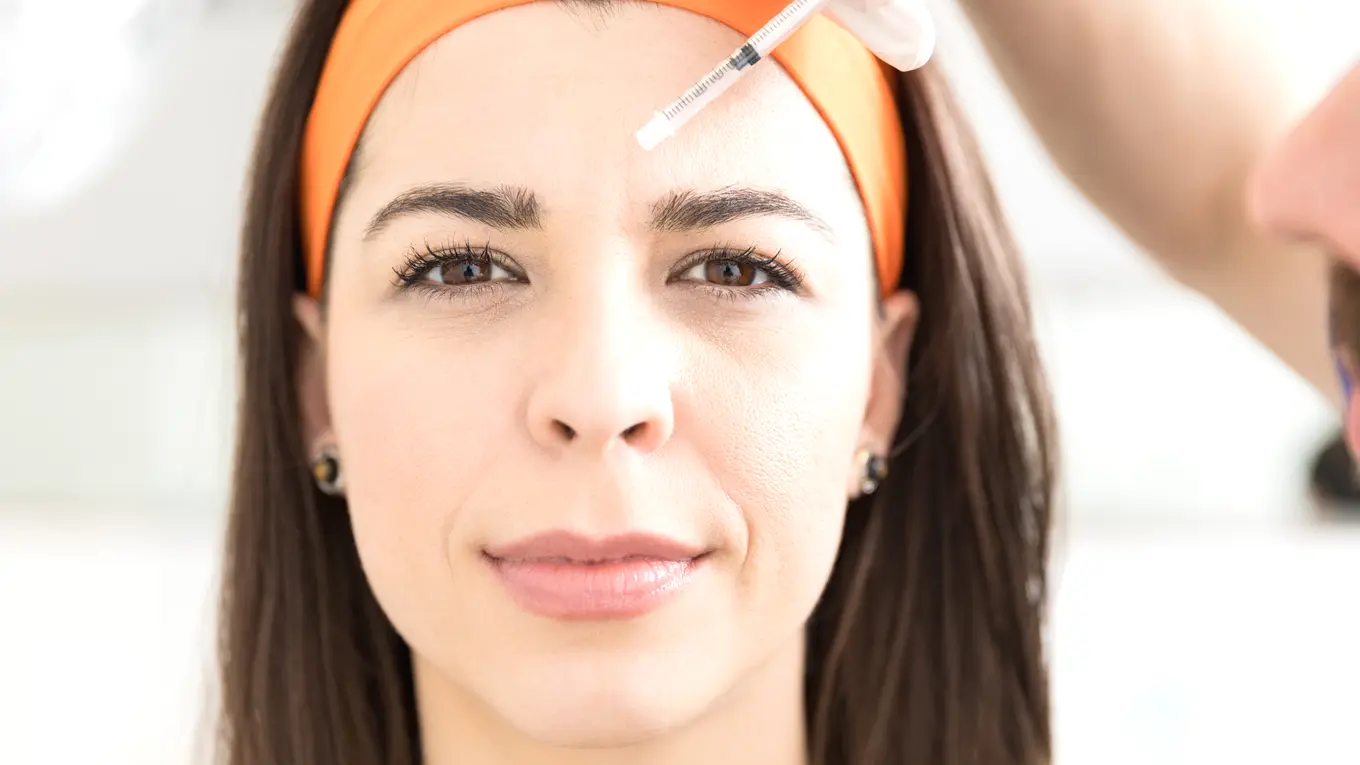 Woman receiving cosmetic injection on forehead