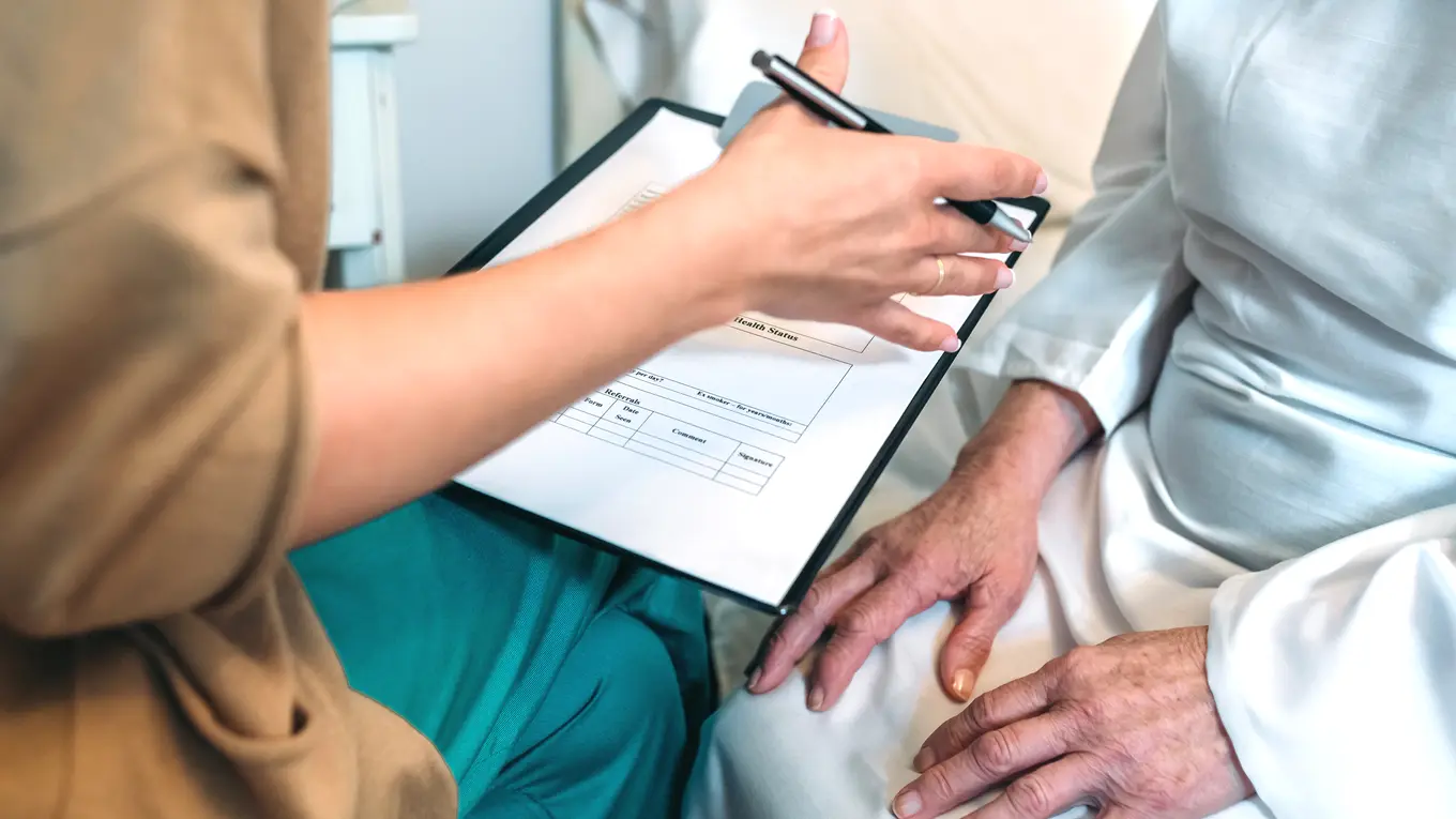 Person filling out medical form with pen
