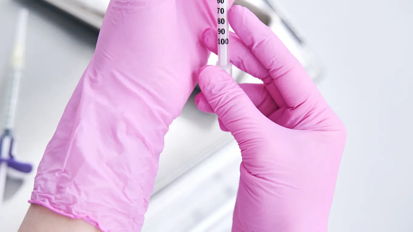 Hands in pink gloves preparing syringe with vial