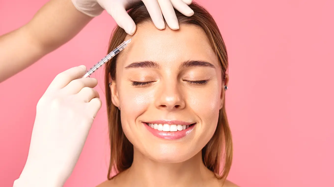 Woman receiving cosmetic injection on forehead