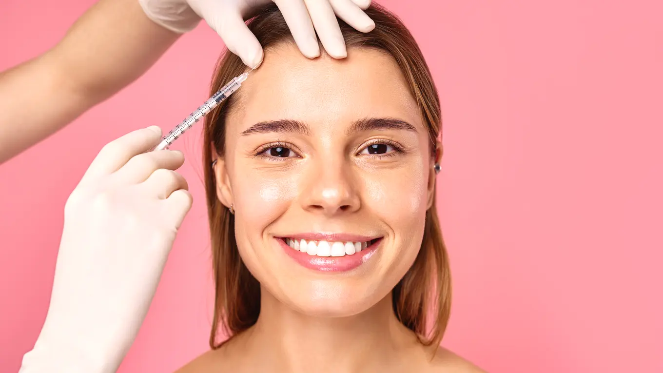Woman receiving cosmetic facial injection on forehead
