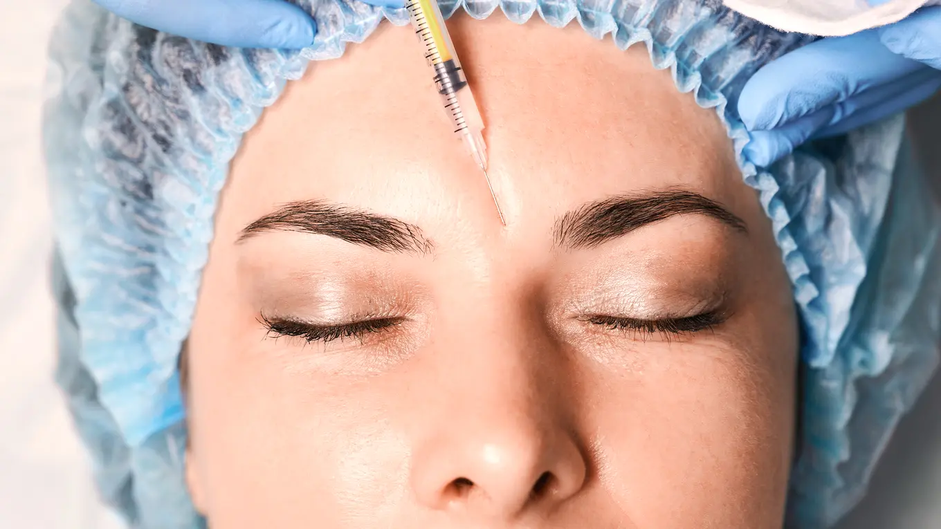 woman receiving forehead injection with syringe