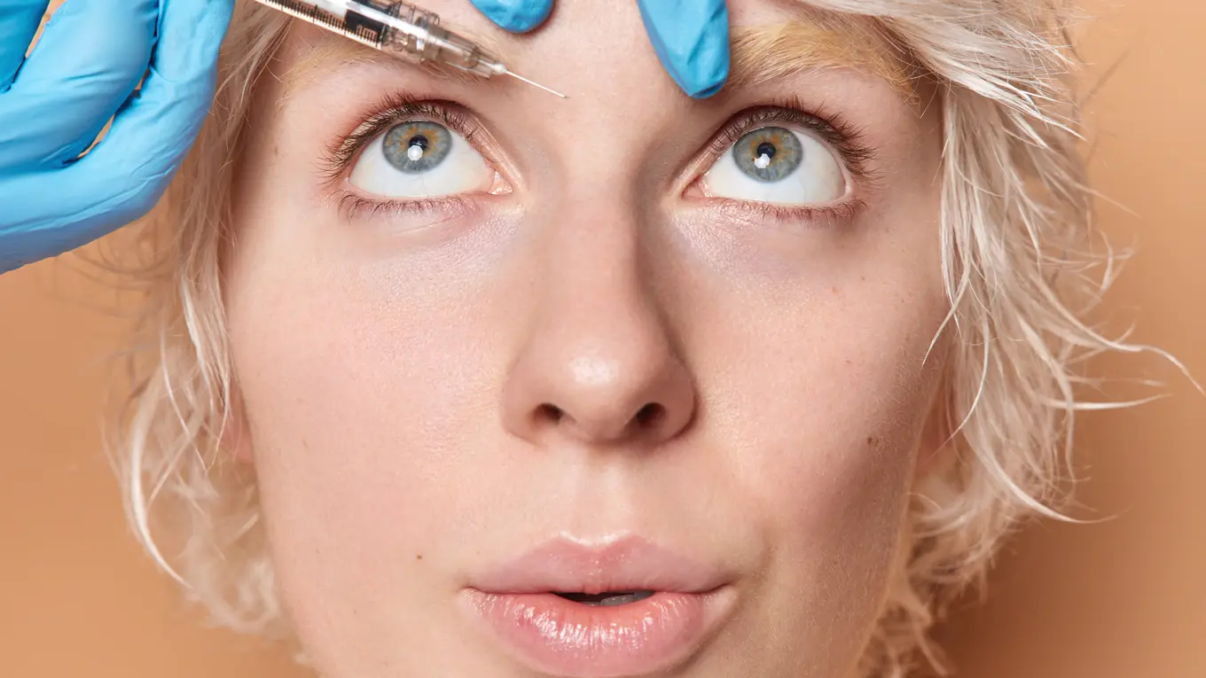 Woman receiving cosmetic injection on forehead