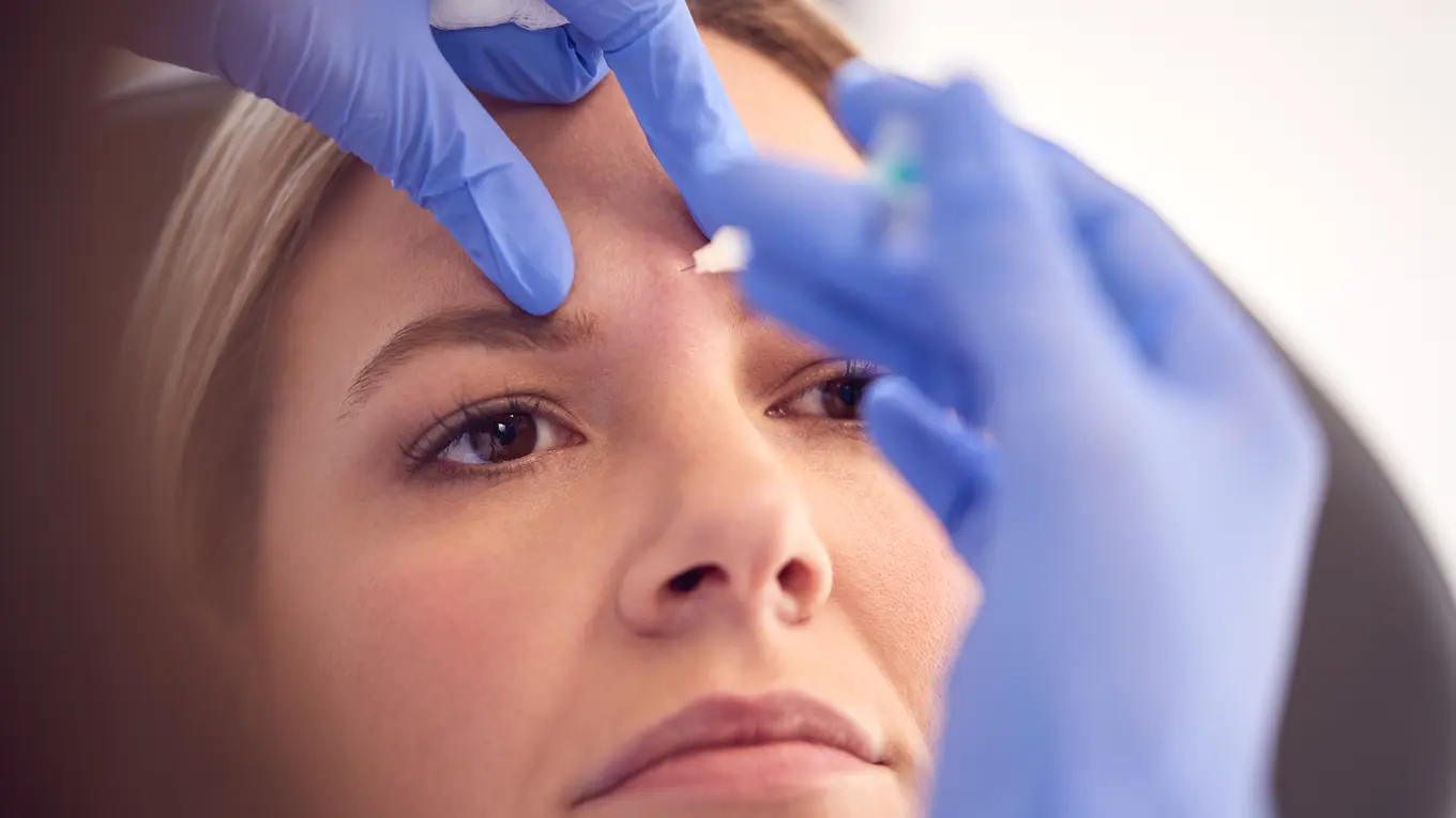 Woman receiving cosmetic injection on forehead