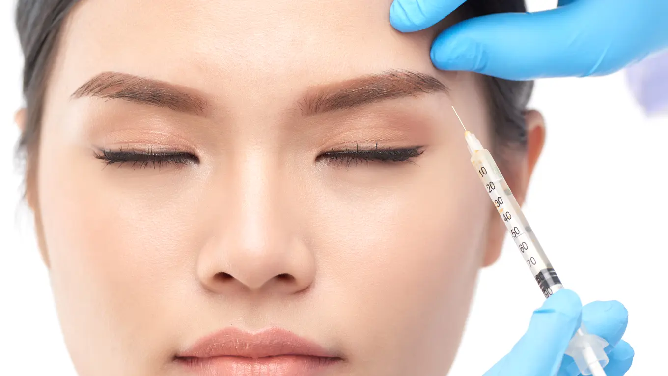 Woman receiving cosmetic injection in forehead