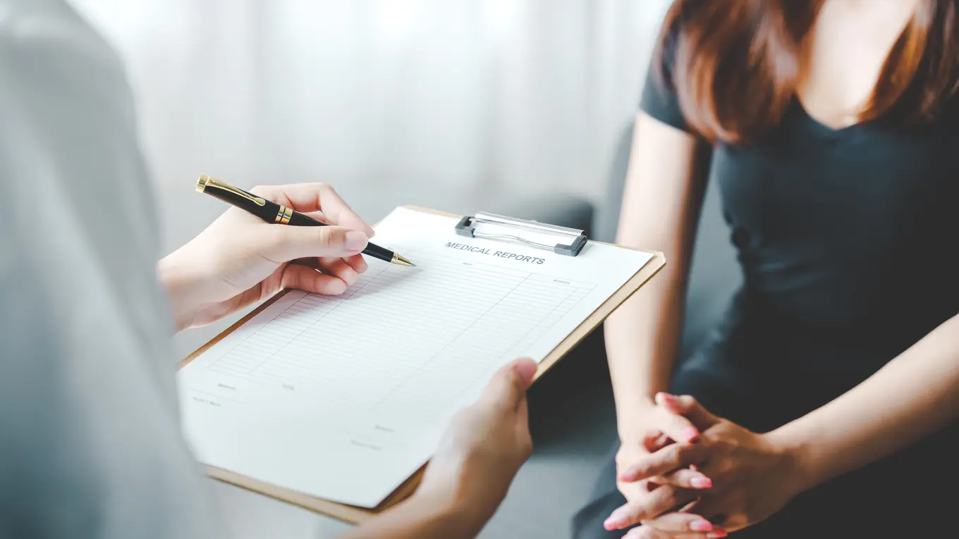 Doctor writing on medical report for patient