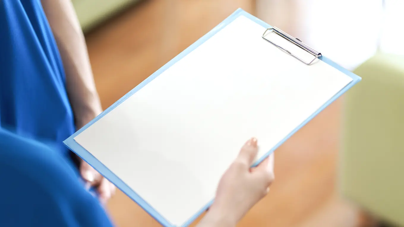 person in blue scrubs holding a clipboard