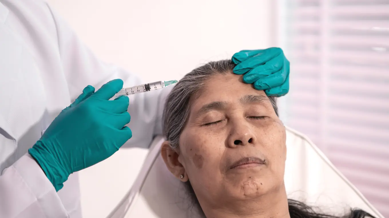 Woman receiving cosmetic injection on forehead