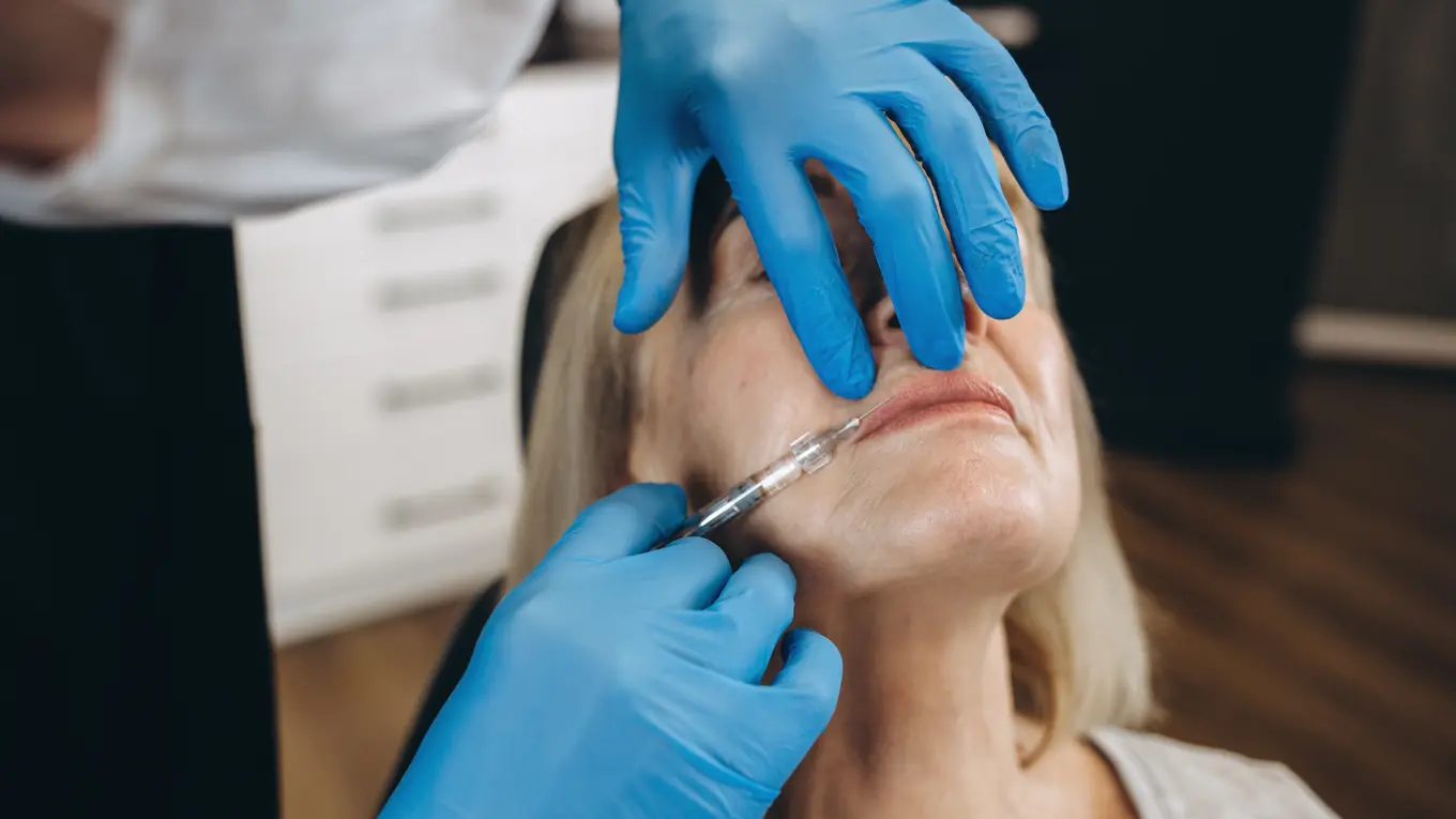Dermatologist injecting filler into woman's lips