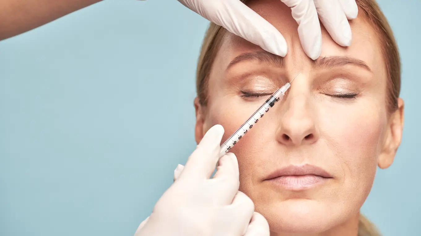 Woman receiving cosmetic injection on forehead