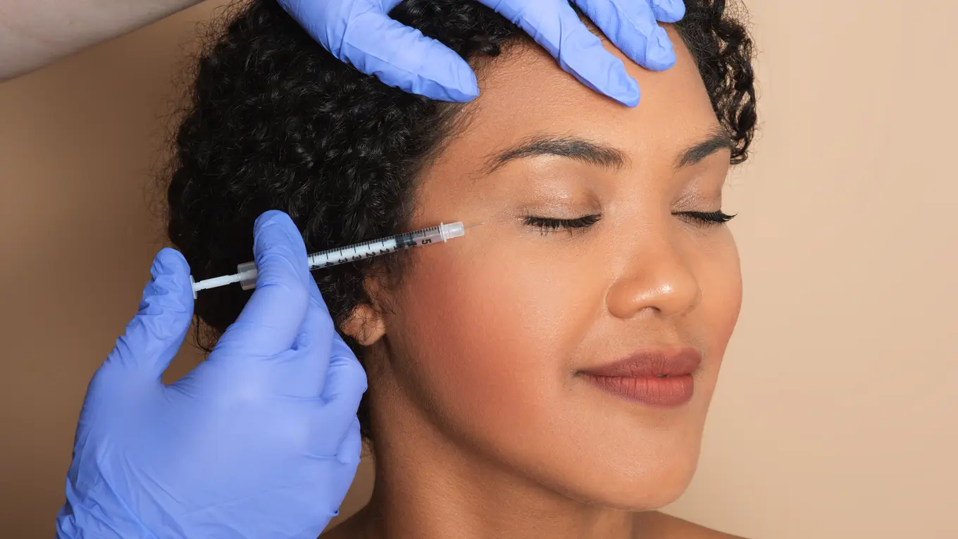 Woman receiving cosmetic injection near eye