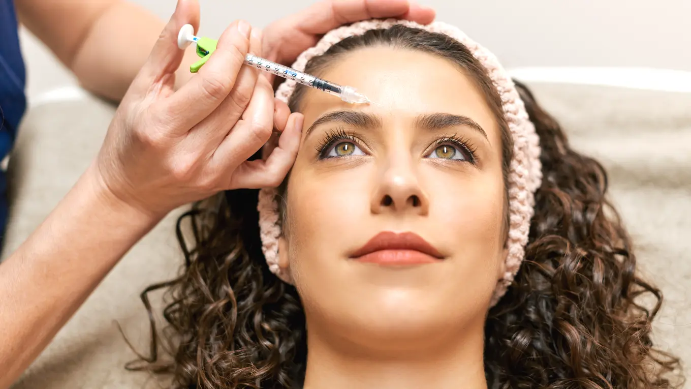 Woman receiving cosmetic injection in forehead