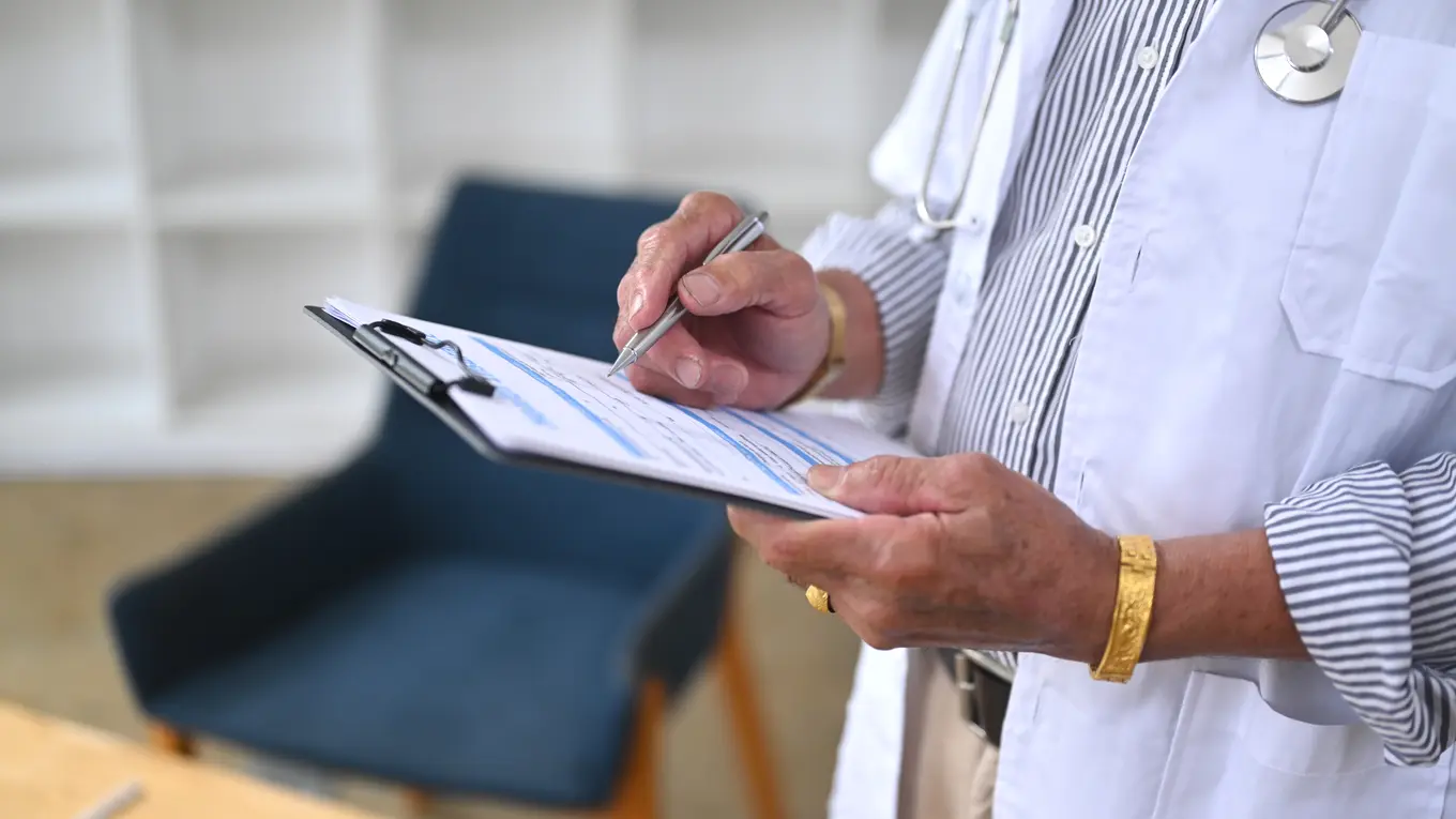 Doctor writing on clipboard in office