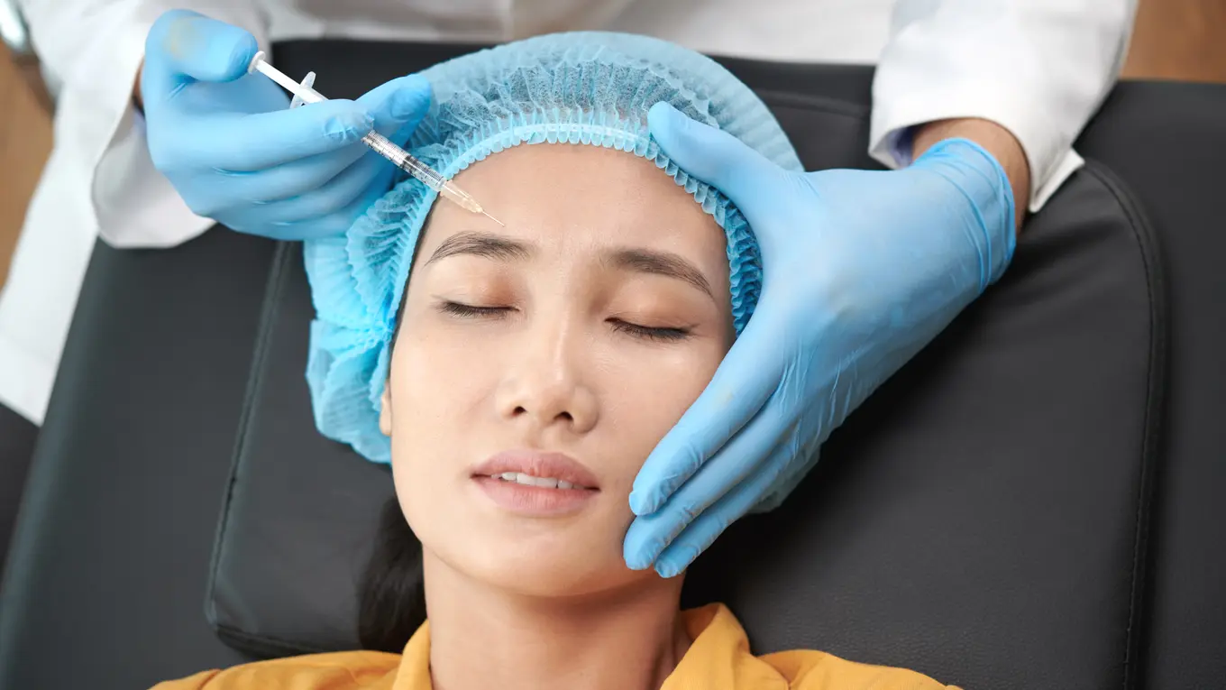 Woman receiving cosmetic injection on forehead