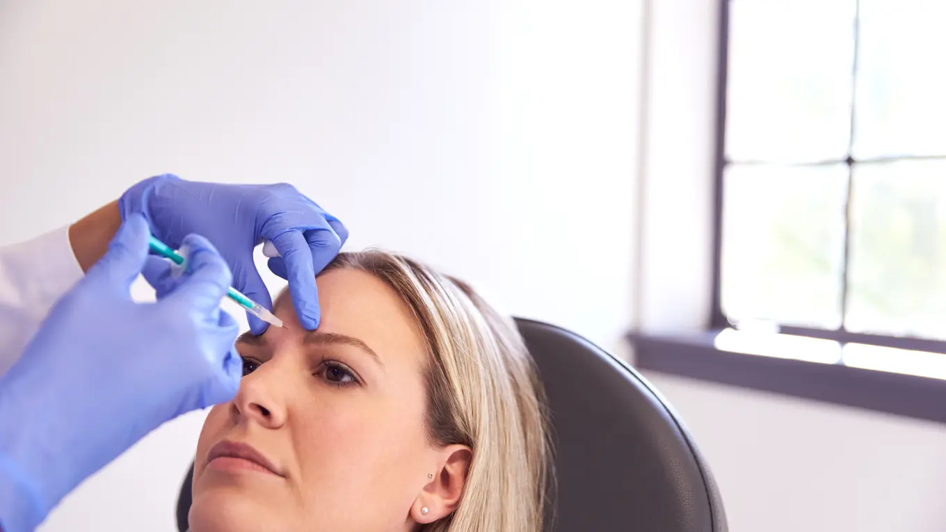 Woman receiving cosmetic injection on forehead