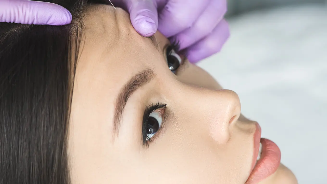Woman receiving cosmetic injection on forehead