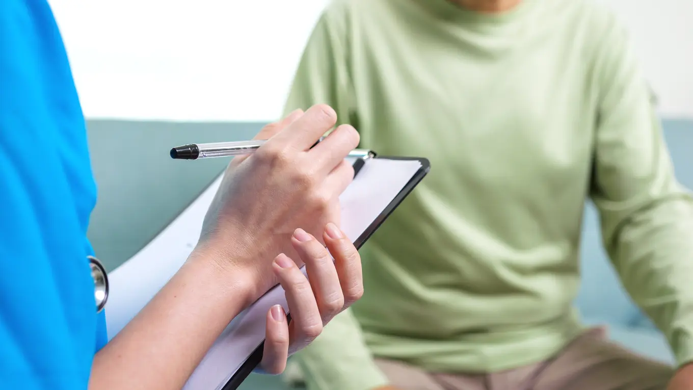 Medical professional writing on clipboard for patient