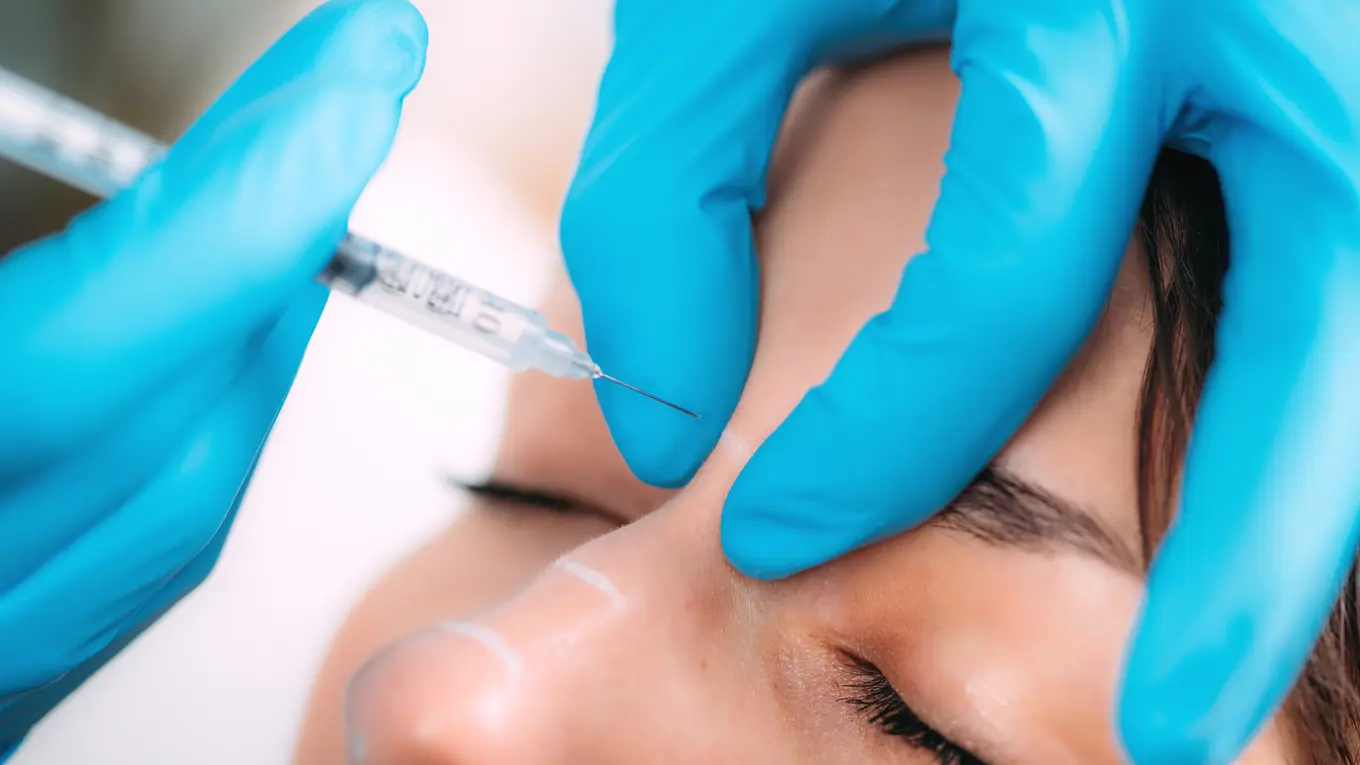 Gloved hand giving injection to nose